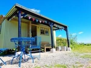 una mesa de picnic azul frente a una casa en Pen Bryn Shepherd Hut, en Hay-on-Wye