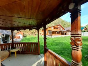 a porch with a wooden roof and green grass at Pensiunea Valea Tonii in Strungari