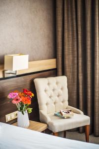 a bedroom with a chair and a vase of flowers at Dunav Plaza Hotel in Ruse