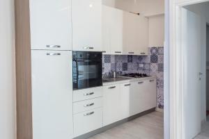 a kitchen with white cabinets and a black appliance at A casa di Marica in Sirolo