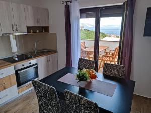 a kitchen with a dining table with chairs and a view at Apartman JAGODA in Senj