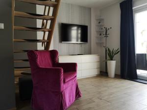 a living room with a chair and a television at Domki Białogóra in Białogóra
