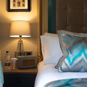 un letto con lampada e orologio su comodino di The Kings Arms and Royal Hotel, Godalming, Surrey a Godalming