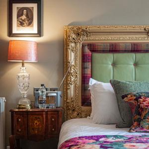 a bed with a gold frame and a lamp on a table at The Kings Arms and Royal Hotel, Godalming, Surrey in Godalming