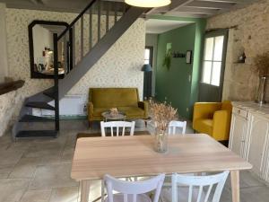 uma sala de jantar com uma mesa e cadeiras e uma escadaria em Le Gîte de Moquesouris em Nazelles