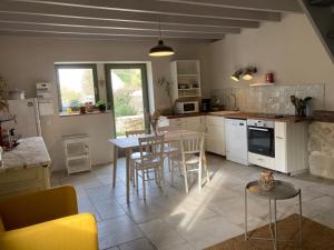 uma cozinha com uma mesa e uma mesa e cadeiras em Le Gîte de Moquesouris em Nazelles