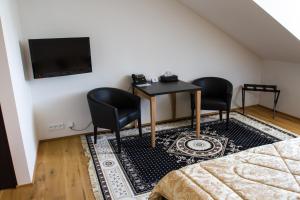 une chambre avec deux chaises, une table et une télévision dans l'établissement Hotel Panství Dlouhá Lhota, à Dlouhá Lhota