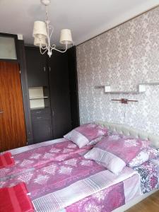 1 dormitorio con 1 cama con sábanas rosas y blancas en Rubin Apartman, en Hajdúszoboszló