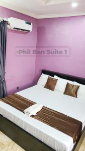 a large bed in a room with a purple wall at PhilBan Suites 1 in Ikeja