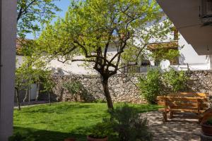 un banco y un árbol en un patio en Apartments Uno, en Mostar