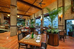 a restaurant with tables and chairs and plants at Fariyas Resort Lonavala in Lonavala