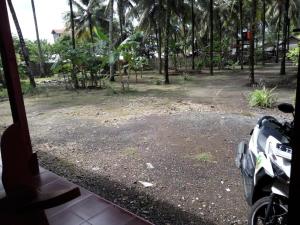 een raam met uitzicht op een tuin met palmbomen bij Pondok Galang in Pangandaran