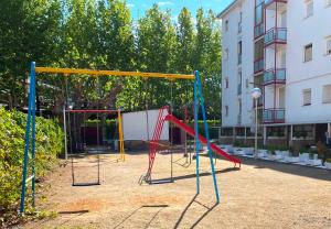 a playground with a swing set in a courtyard at Apartamentos Córcega Palmyra in Salou