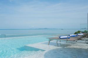 Bayphere Hotel Pattaya في نا جومتين: مسبح مع طاولة وكرسي في الماء