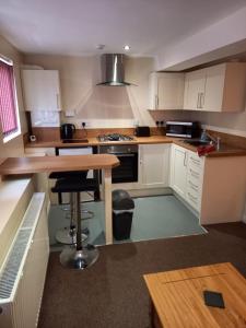 eine Küche mit weißen Schränken und einem Holztisch in der Unterkunft clazzers apartment 3 in Bridlington