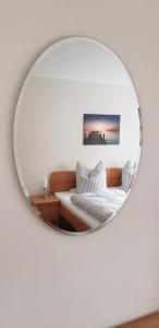 ein Spiegel, der ein Schlafzimmer mit einem Bett und einem Sofa reflektiert in der Unterkunft An den Elbwiesen in Dresden