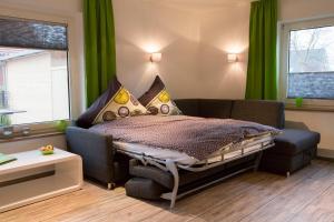 a bedroom with a bed and a couch and a window at Mienhus Apartments Ferienwohnung Fiete in Norden