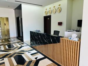an office lobby with a reception desk and clocks on the wall at Falcon Grand Hotel in Al Ḩadd