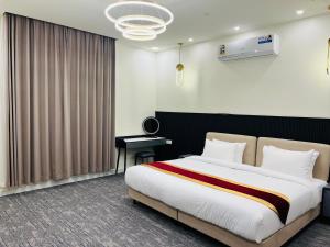 a bedroom with a large bed and a desk at Falcon Grand Hotel in Al Ḩadd