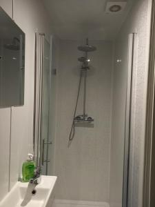 a white bathroom with a shower and a sink at clazzers apartment 3 in Bridlington