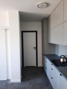 a kitchen with white cabinets and a white door at Apartament nad jeziorem Bory Tucholskie Charzykowy in Charzykowy