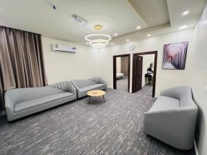 a living room with couches and a table and a mirror at Falcon Grand Hotel in Al Ḩadd