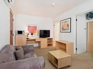 
a living room filled with furniture and a tv at Country Plaza Motel Taree in Taree
