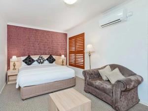 a bedroom with a bed and a couch and a chair at Country Plaza Motel Taree in Taree
