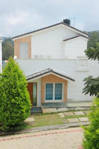 ein weißes Haus mit Bäumen davor in der Unterkunft Hotel Aradhana Inn in Yercaud