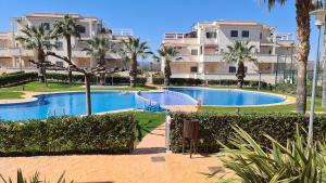 a swimming pool in a resort with palm trees and buildings at Apartamentos Arenas Altamar in Alcossebre
