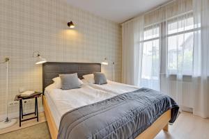 a bedroom with a large bed and a window at Dom & House Apartment Neptun Park Comfort in Gdańsk