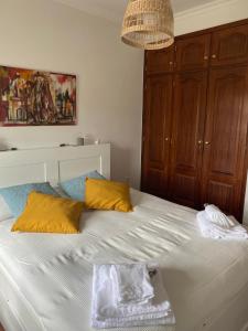 uma cama com almofadas amarelas e azuis num quarto em Casa da Azinhaga em Alenquer