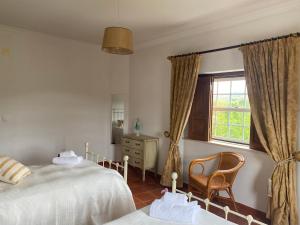 a bedroom with a bed and a chair and a window at Casa da Azinhaga in Alenquer