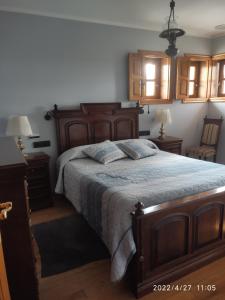 a bedroom with a large wooden bed and two lamps at Albergueria Frade in O Cebrero