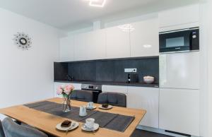 a kitchen with a wooden table with chairs and a kitchen with white cabinets at Villa Linett in Siófok