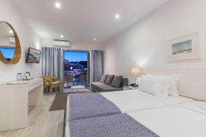 a white bedroom with a large bed and a living room at Hotel Baltum in Albufeira