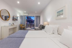 a white bedroom with a large bed and a living room at Hotel Baltum in Albufeira