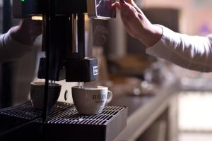 a person is making coffee in a coffee machine at Alevic Hotel Sirmione in Sirmione