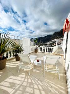 Un patio con sillas y una mesa en el balcón. en Luxury penthouse with breathtaking views and huge private terraces, en Puerto de Santiago