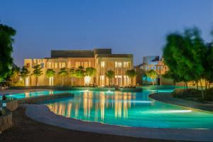 - une piscine en face d'un bâtiment la nuit dans l'établissement Zulal Wellness Resort by Chiva-Som, à Ar Ruʼays