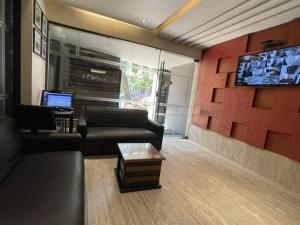 a living room with a couch and a tv at Hotel Aston International in Kolkata
