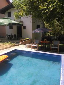 a swimming pool with a table and chairs and an umbrella at Relax house in Visoko