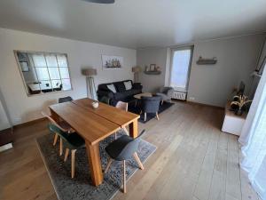 een woonkamer met een tafel en stoelen en een bank bij Maison d'Alice - avec SPA in Bayeux