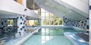 a large swimming pool in a building with a large window at Hotel Fit Fun in Harrachov