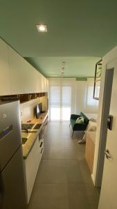 a kitchen with white cabinets and a room with a bed at Apartamento para renovar as energias - Cama Queen in São Paulo