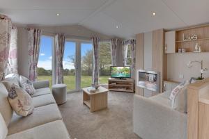 ein Wohnzimmer mit einem Sofa und einem TV in der Unterkunft The Lakes Rookley in Rookley