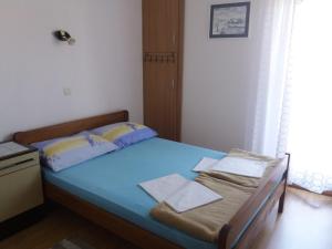 ein kleines Schlafzimmer mit einem Bett mit blauer Bettwäsche und Kissen in der Unterkunft Apartment Visnja -near Queen Beach in Nin