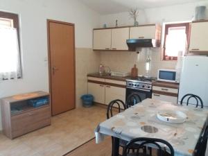 eine Küche mit einem Tisch und eine Küche mit einem Kühlschrank in der Unterkunft Apartment Visnja -near Queen Beach in Nin