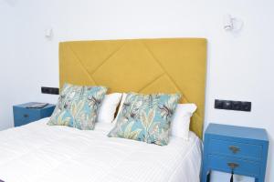 łóżko z żółtym zagłówkiem i 2 niebieskimi stolikami nocnymi w obiekcie Casa Rural La Lerena w mieście Casar de Cáceres