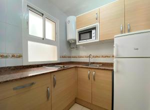a kitchen with wooden cabinets and a white refrigerator at Apartamentos Hesperia Palmyra in Salou